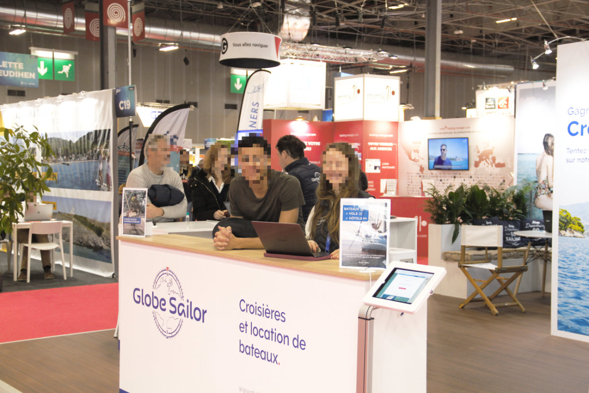 Moi, Hugo, souriant à la caméra au comptoir du stand de GlobeSailor.